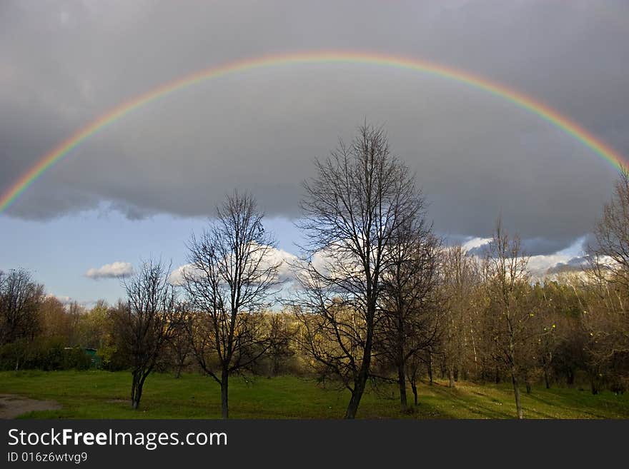 The cloudy sky and autumn rainbow above forest. The cloudy sky and autumn rainbow above forest.