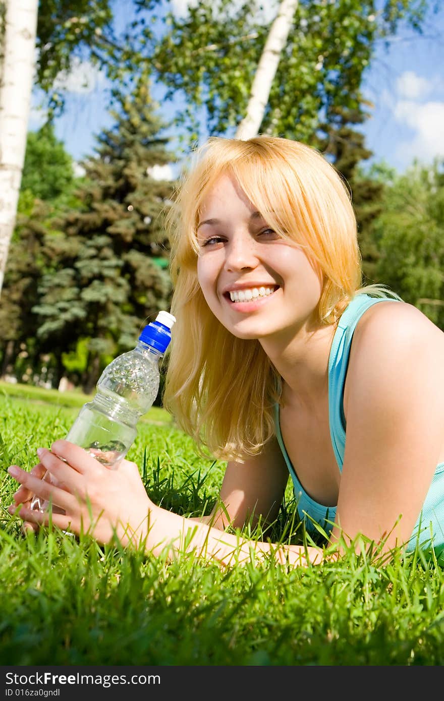 Pretty woman drinking water on the summer glade