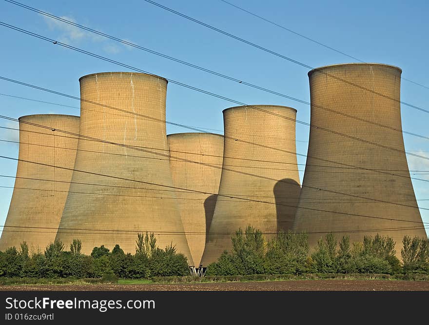 The cooling towers of a power station against a blue sky. The cooling towers of a power station against a blue sky