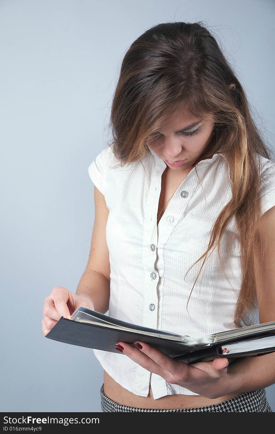 Young student girl looking to textbook on grey background