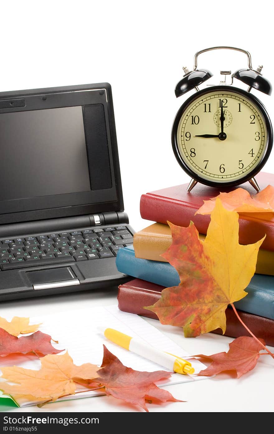 Pile of books, notebook, alarm clock and autumn leaves on a white background. Pile of books, notebook, alarm clock and autumn leaves on a white background.