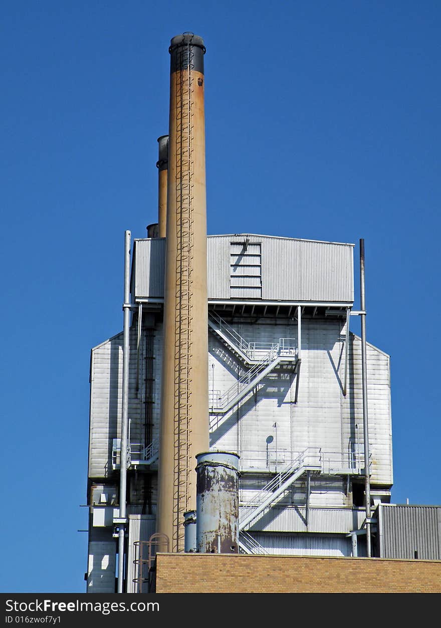 Industrial smokestack against a summer blue sky. Industrial smokestack against a summer blue sky.