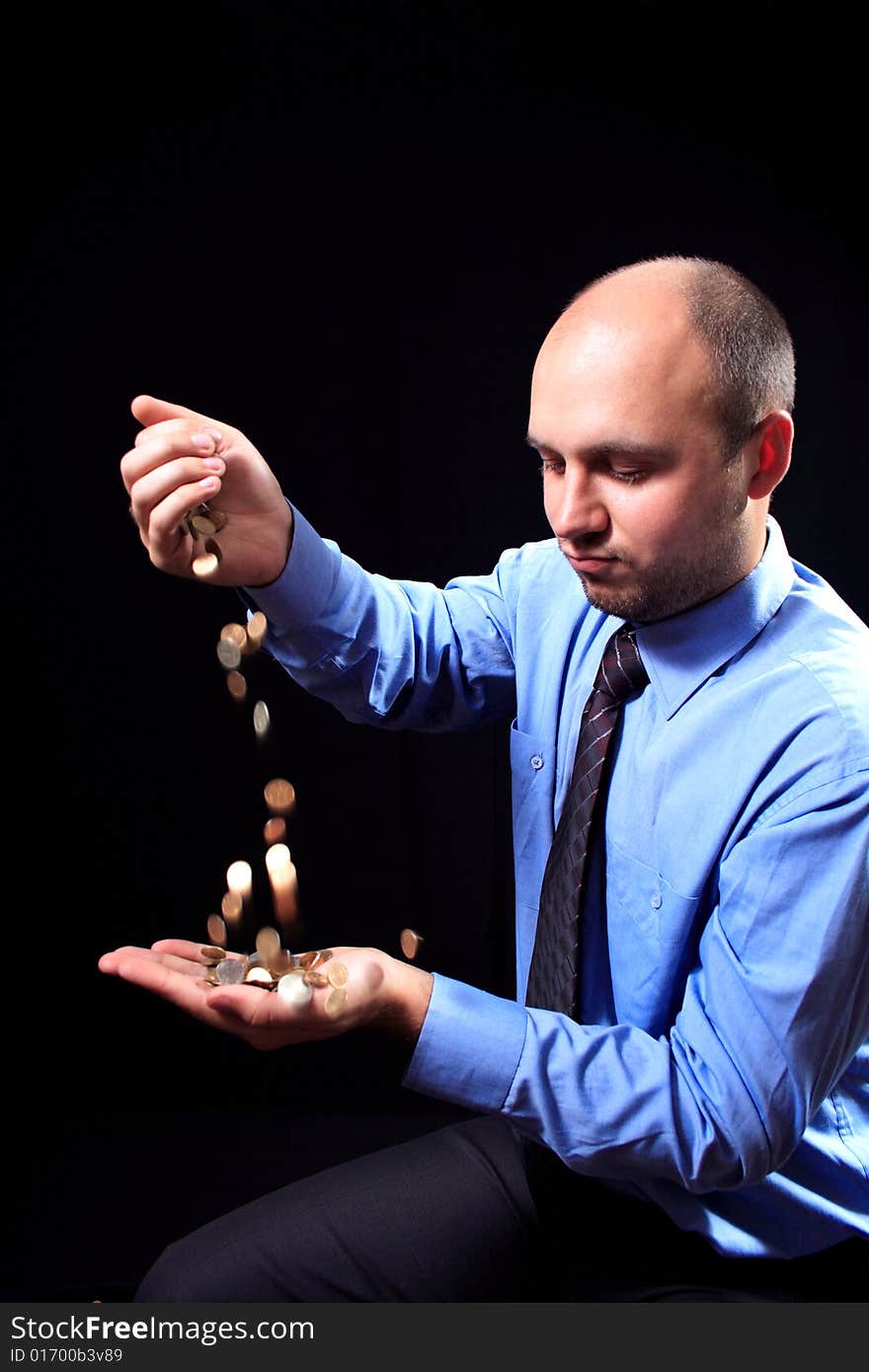 Man in a shirt and a tie fills coins, on a black background. Man in a shirt and a tie fills coins, on a black background