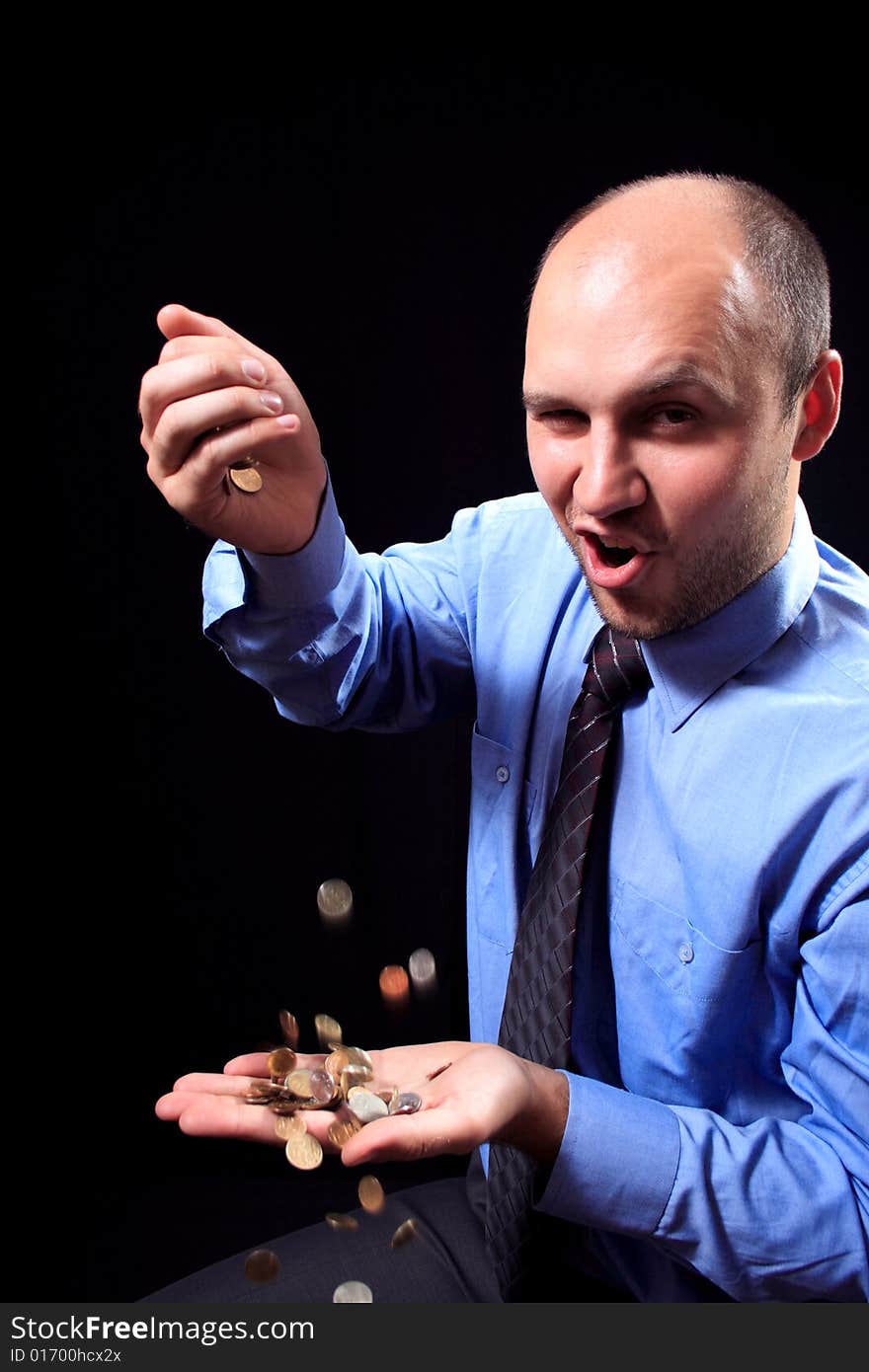 Man in a shirt and a tie fills coins, on a black background. Man in a shirt and a tie fills coins, on a black background