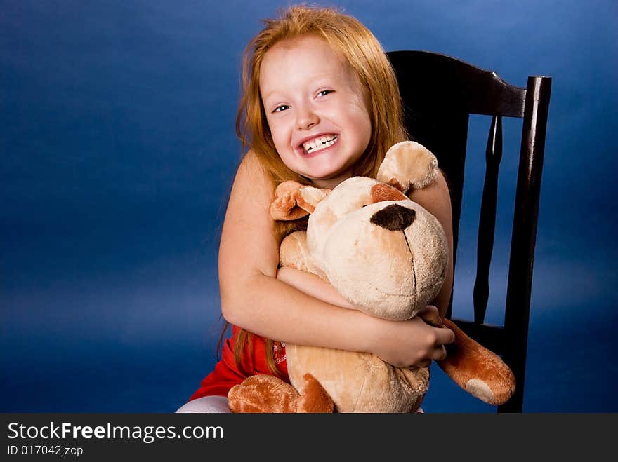 Beautiful ginger girl with a toy against blue background. Beautiful ginger girl with a toy against blue background