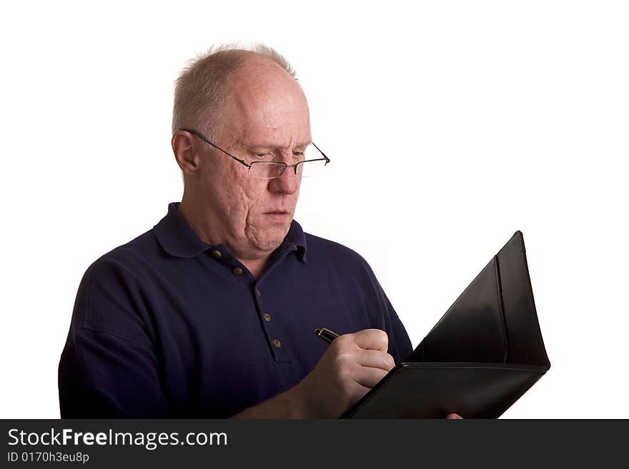 An old bald guy wearing glasses writing notes in a notebook. An old bald guy wearing glasses writing notes in a notebook