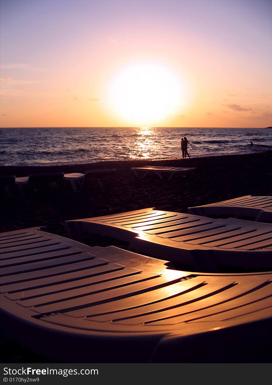 Chaise longues ashore over sunset sky