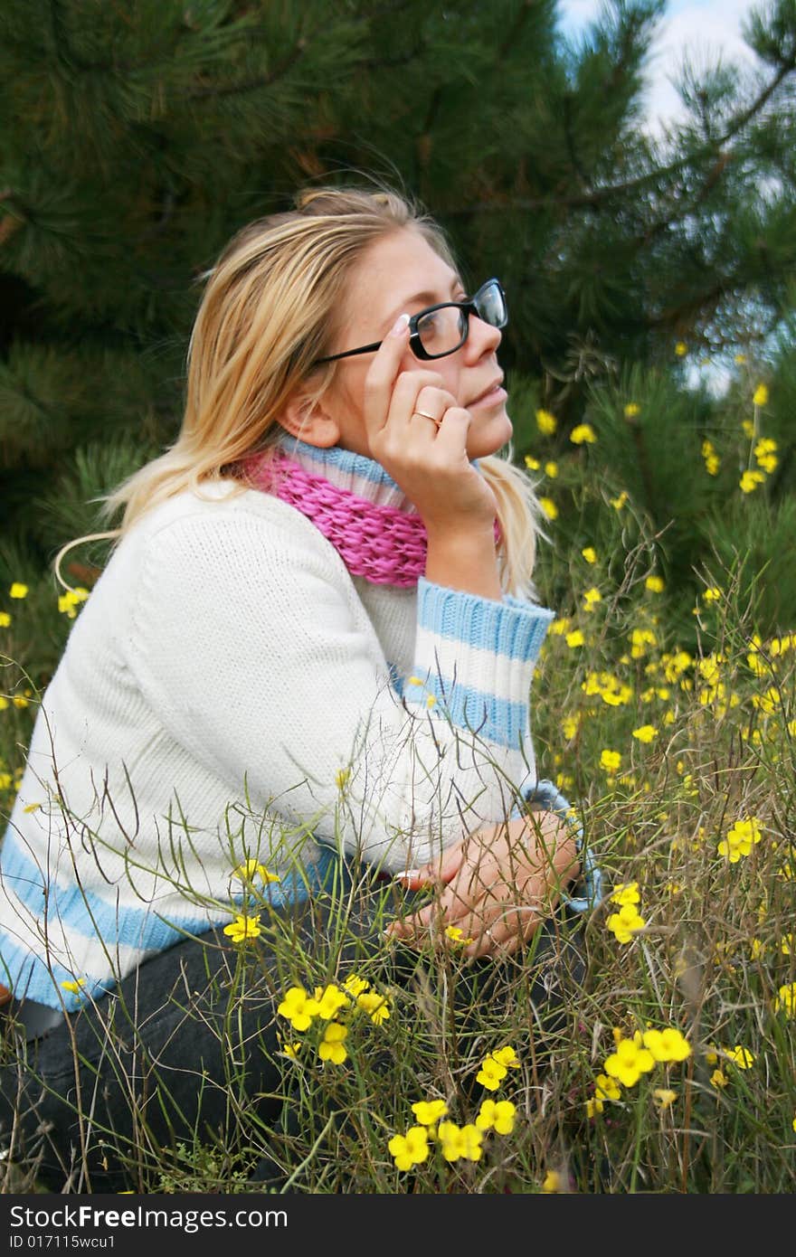 The girl sits on a lawn   in an environment of yellow colours. The girl sits on a lawn   in an environment of yellow colours