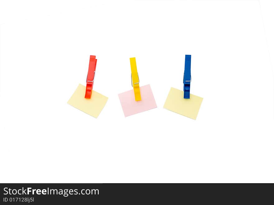 Three pegs holding coloured scratch paper isolated on white. Three pegs holding coloured scratch paper isolated on white