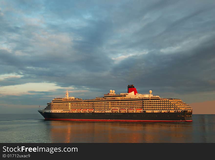 Cruise ship in a sea against a dramatic sunset sky