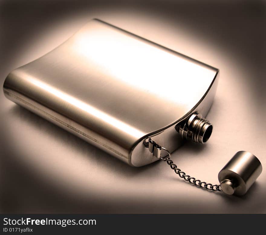 Metal chrome flask lying on its side with the lid off with dark edges