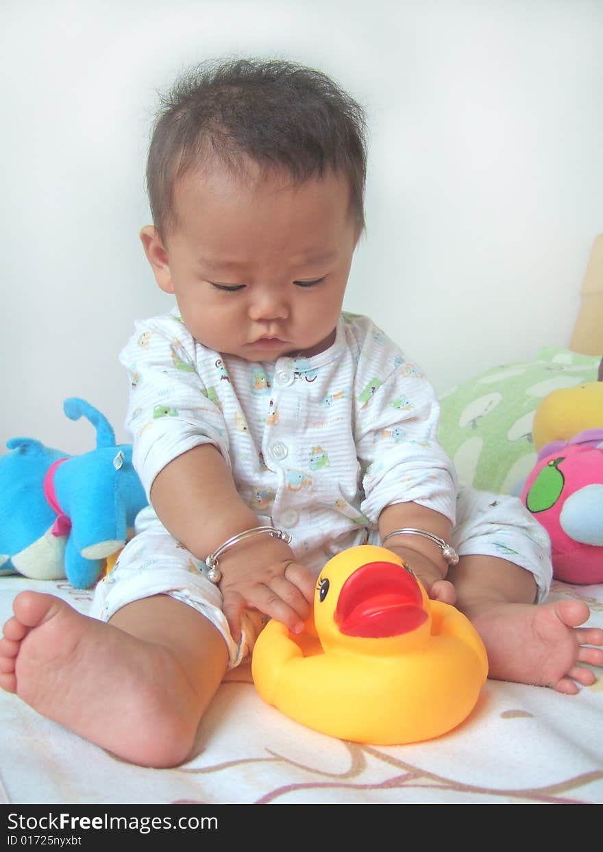 Pretty baby and toy ducks on a bed