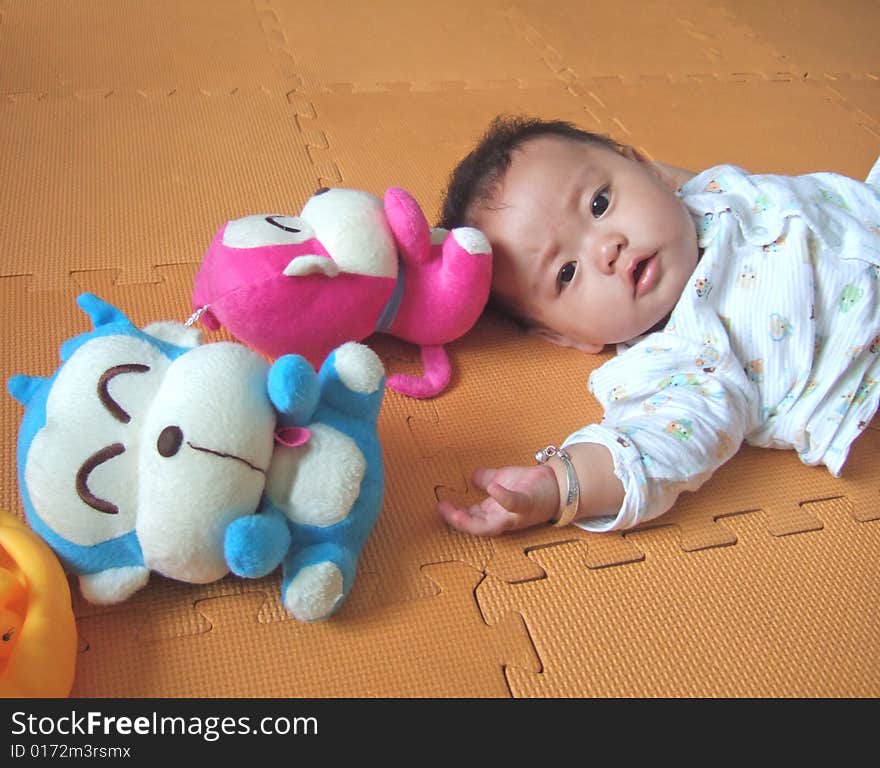 Pretty baby is playing with toys on a yellow mat. Pretty baby is playing with toys on a yellow mat