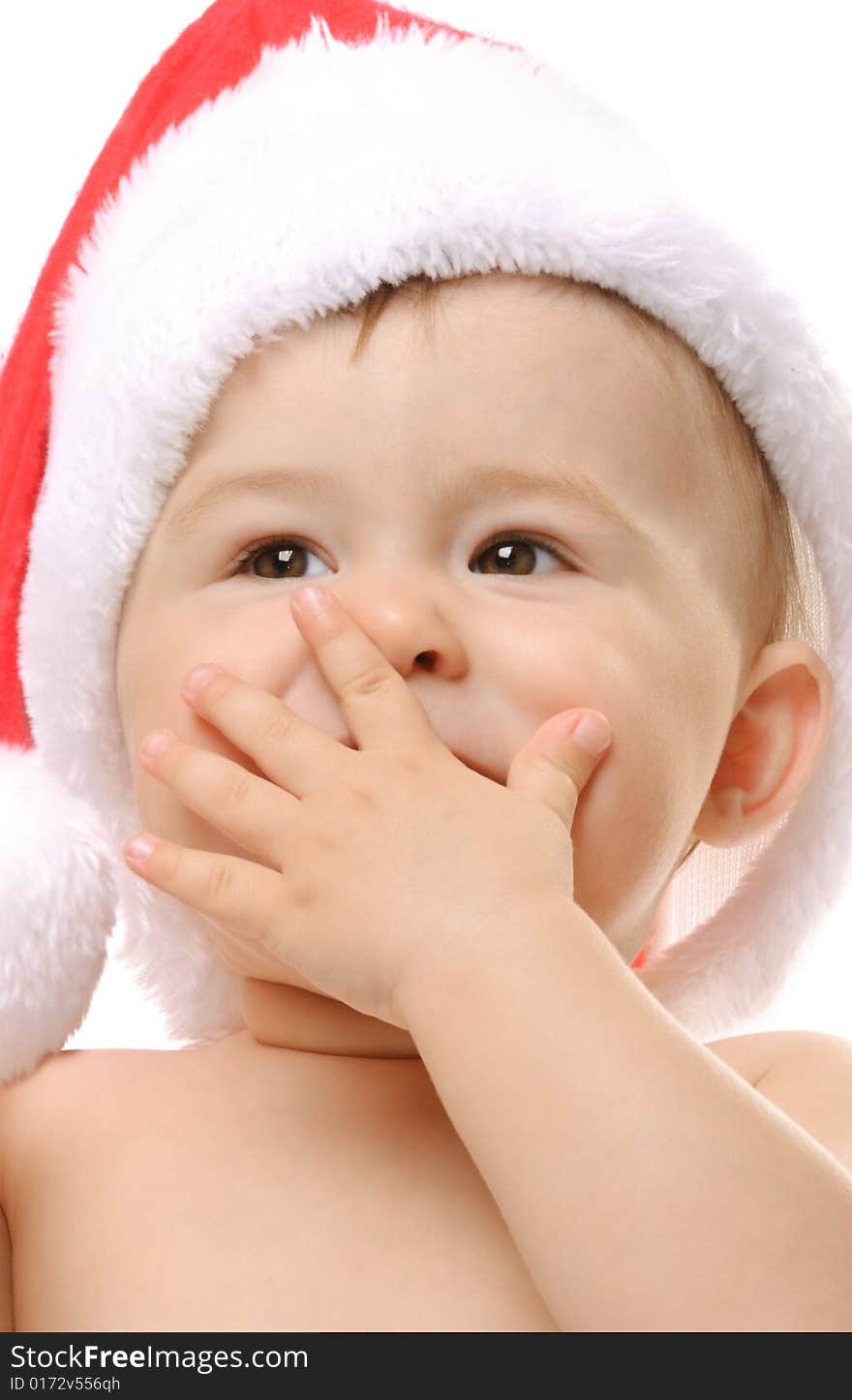 Cute toddler in Santa`s hat covers a mouth with a hand. Cute toddler in Santa`s hat covers a mouth with a hand