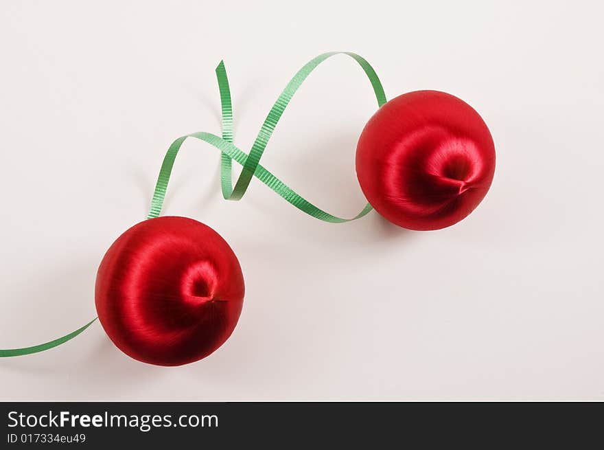 Two red Christmas Ornaments with curly green Ribbon on a white background. Two red Christmas Ornaments with curly green Ribbon on a white background