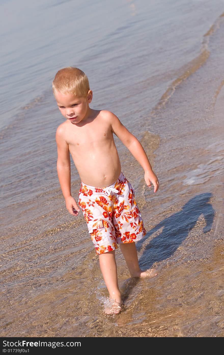 Boy walking at the beach with nothing but his shadow following him