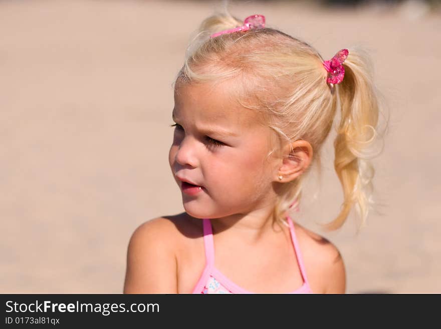 Little girl sitting in the sand at the beach. Little girl sitting in the sand at the beach