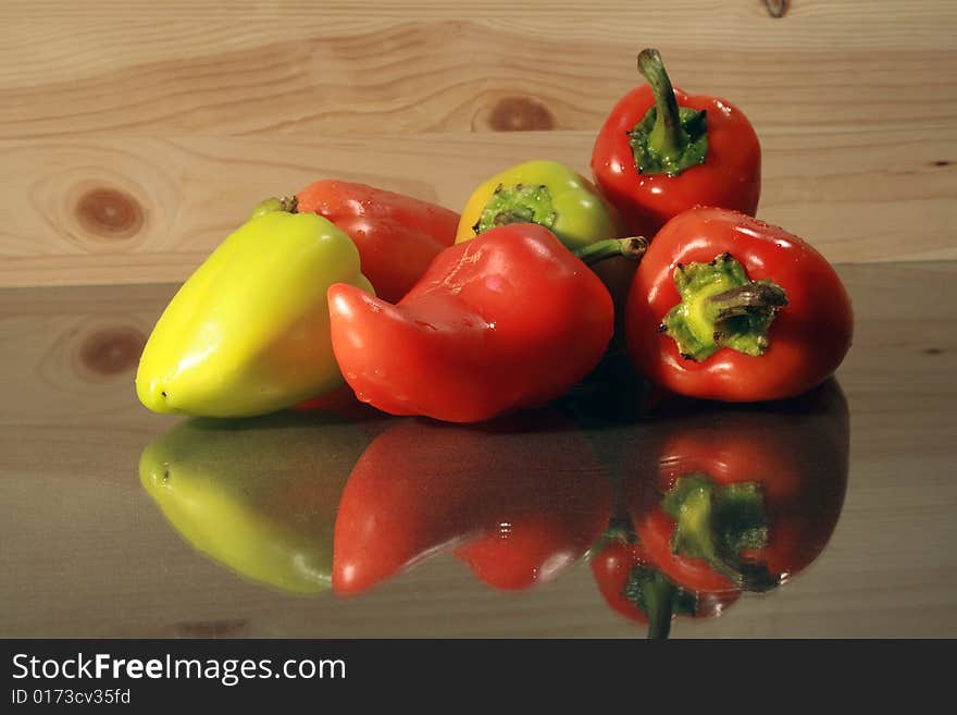 Red and green sweet peppers lying on glassy table