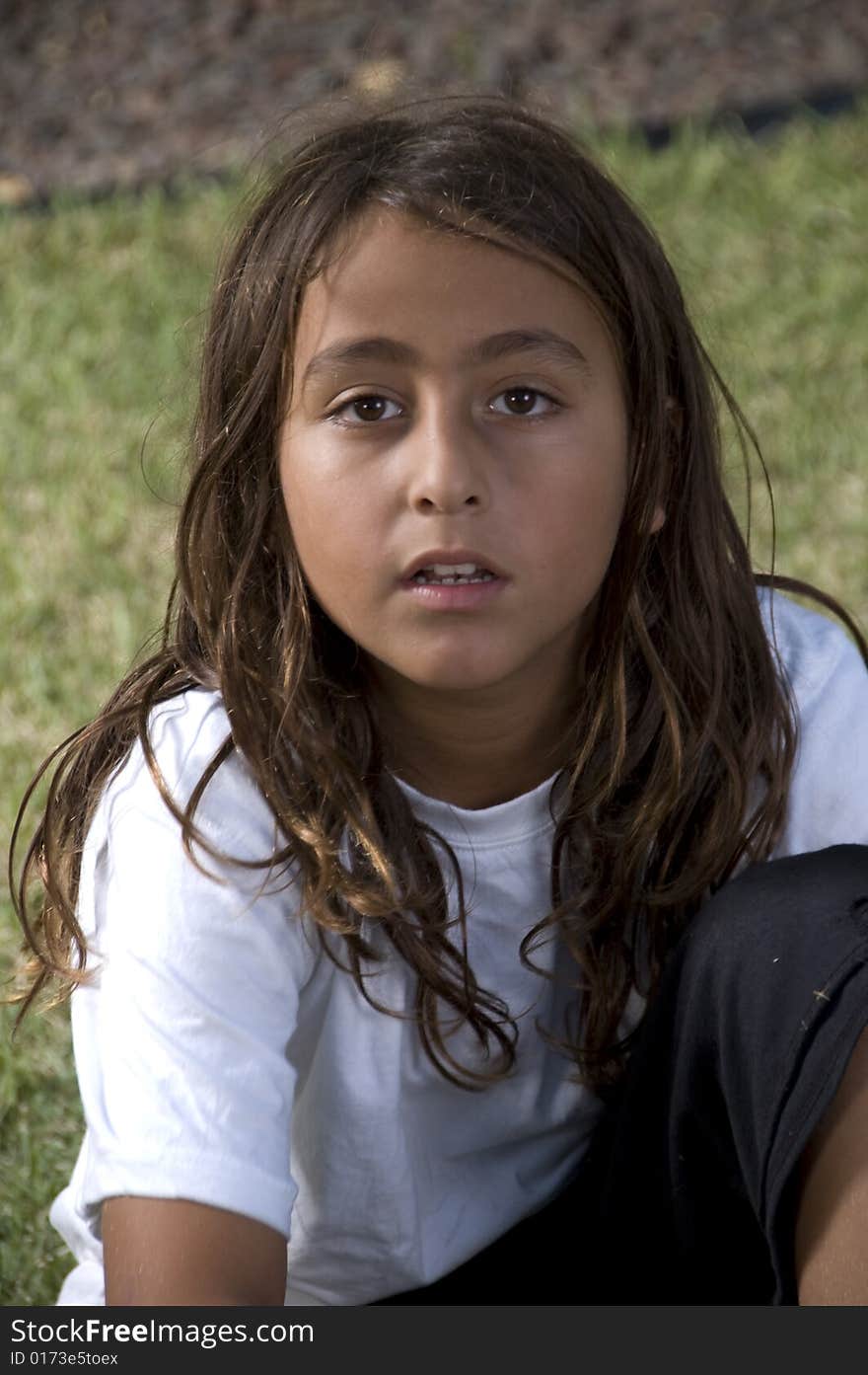 Adorable young boy sitting on green grass looking to camera. Adorable young boy sitting on green grass looking to camera