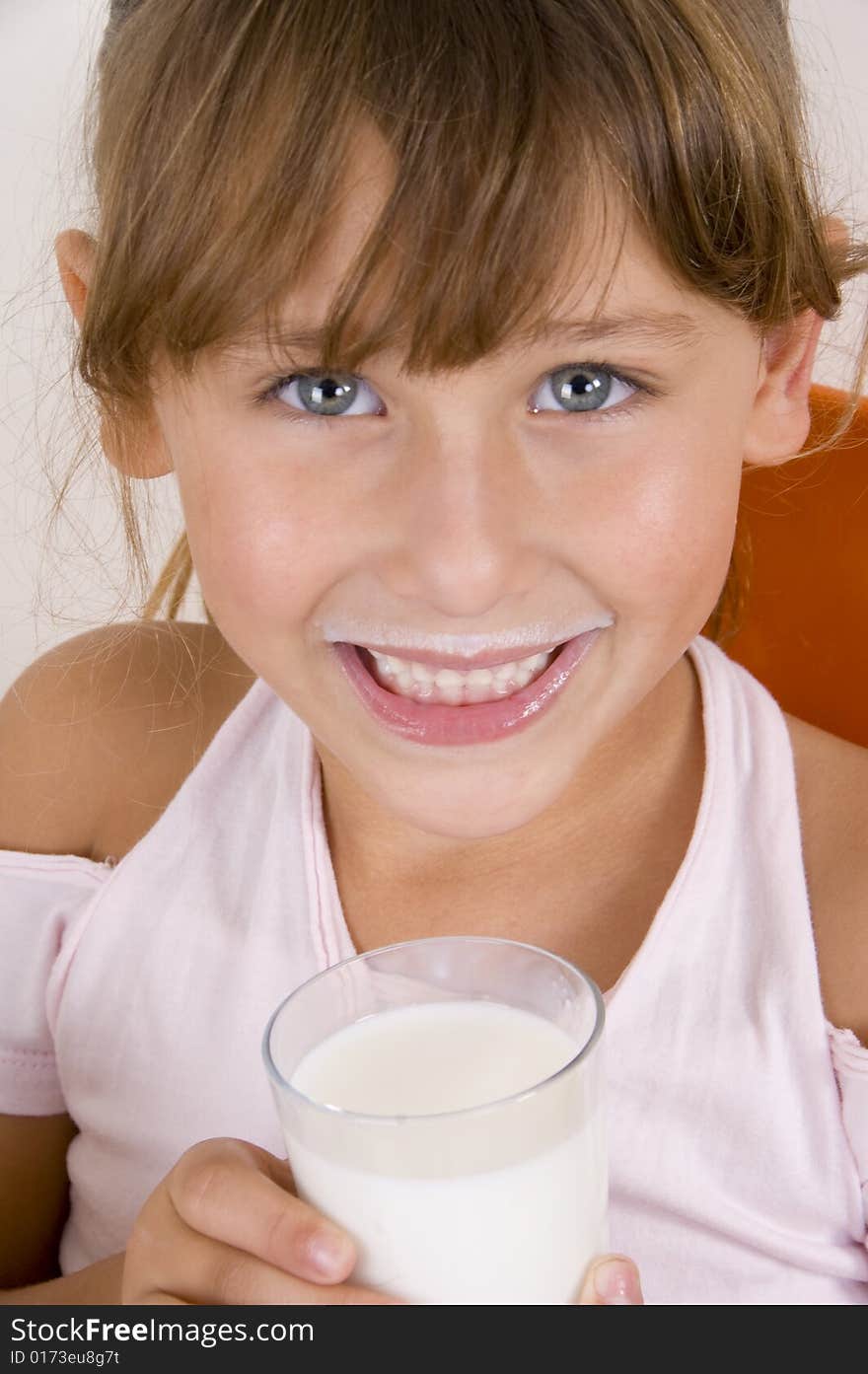 Smiling girl with glass of milk looking