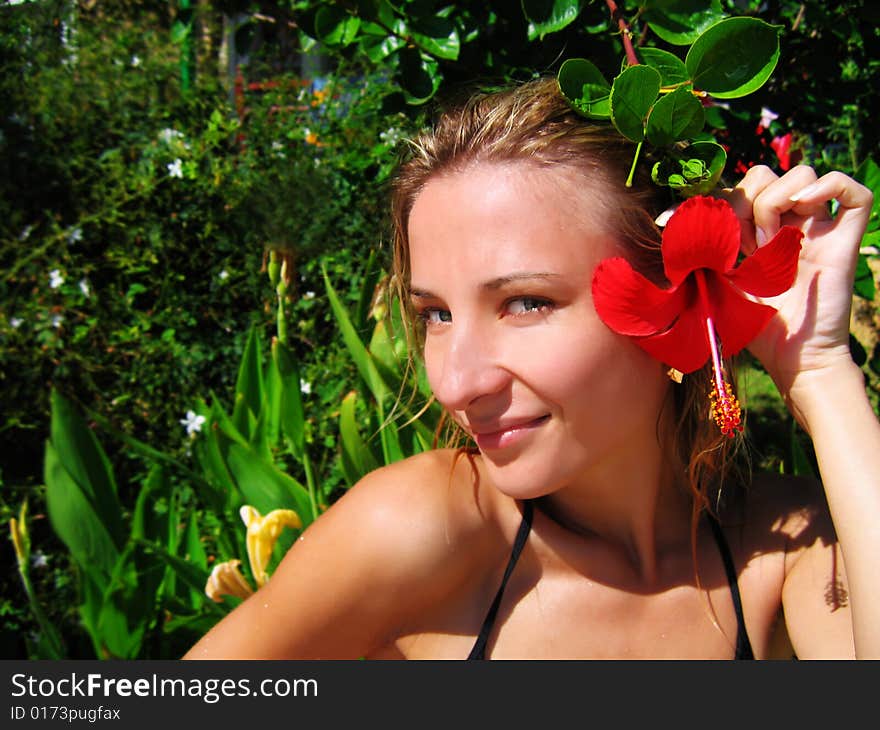 Woman with red hibiscus over green. Woman with red hibiscus over green