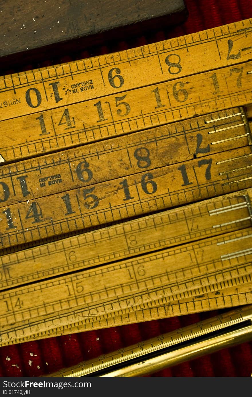 Three old wooden rules in a red background of a workshop