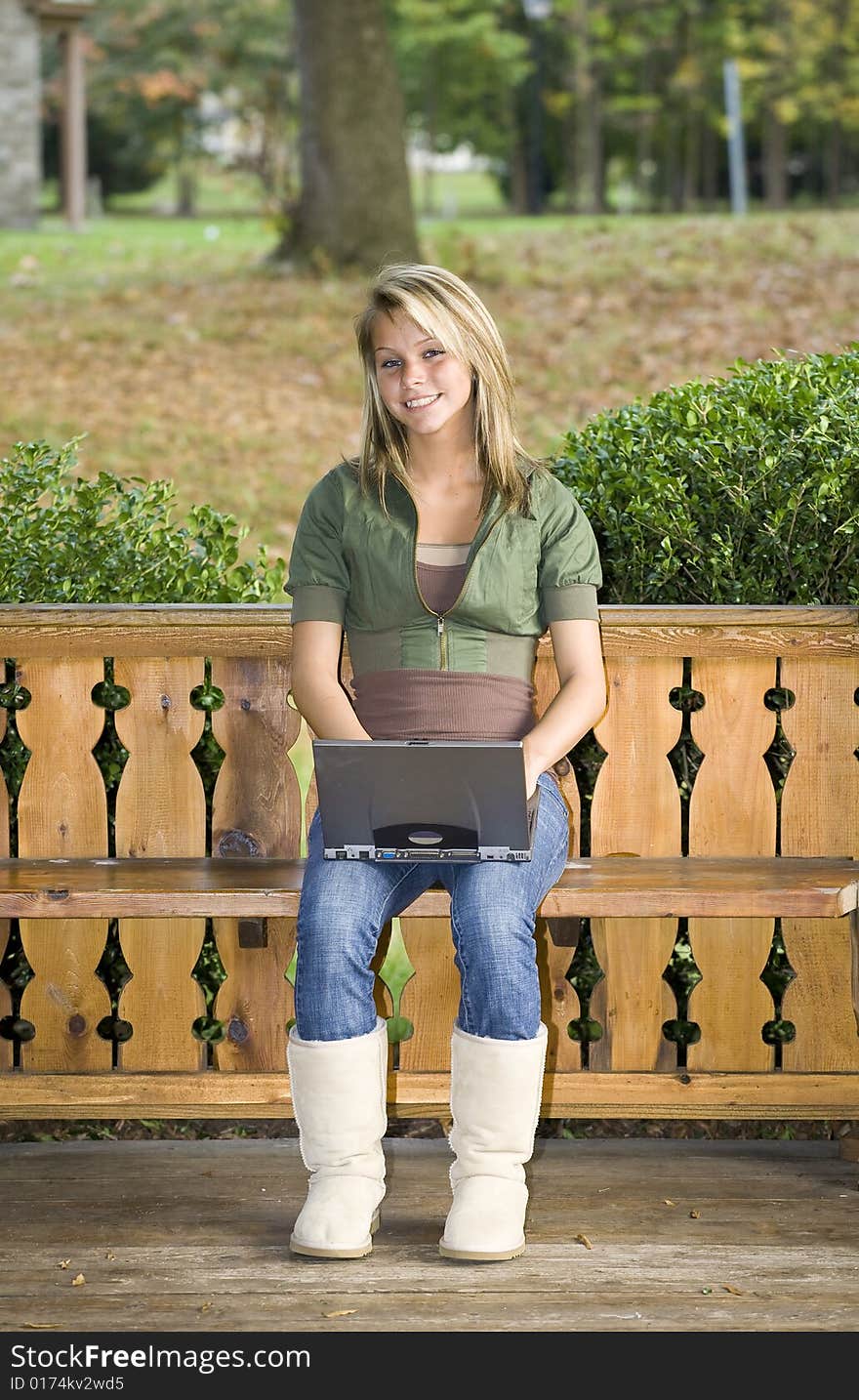 A beautiful blond teenage girl using her laptop in the park