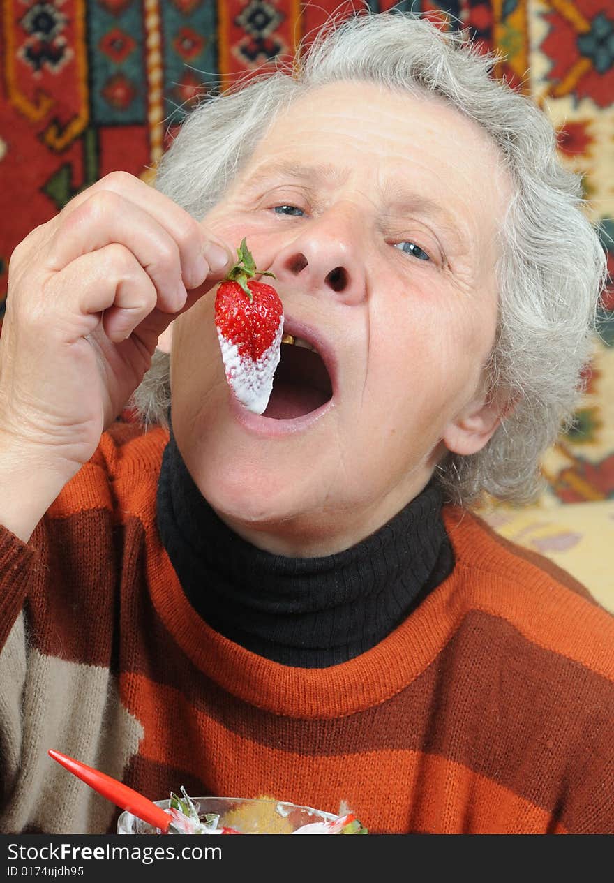 Grandmother eats a ripe strawberry. Grandmother eats a ripe strawberry