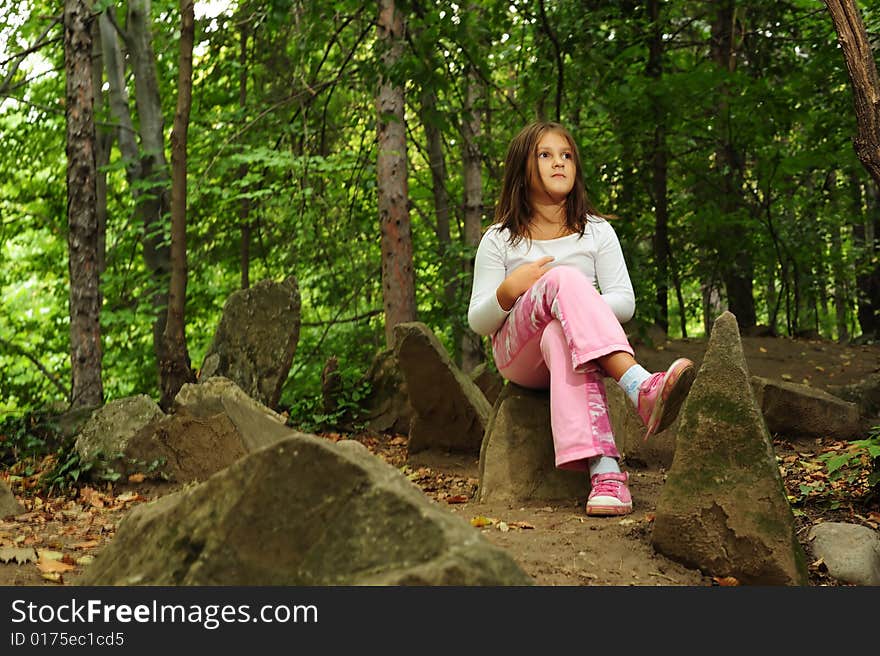 A little girl standing on a rock in forest. A little girl standing on a rock in forest