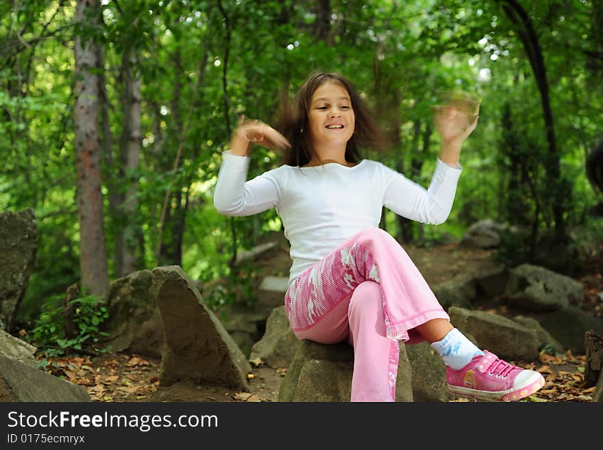 A little girl standing on a rock in forest, motion blur effect. A little girl standing on a rock in forest, motion blur effect