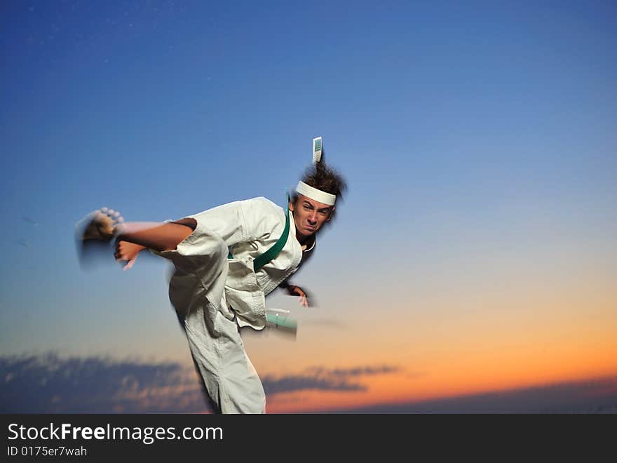 Young boy in karate uniform training at sunset