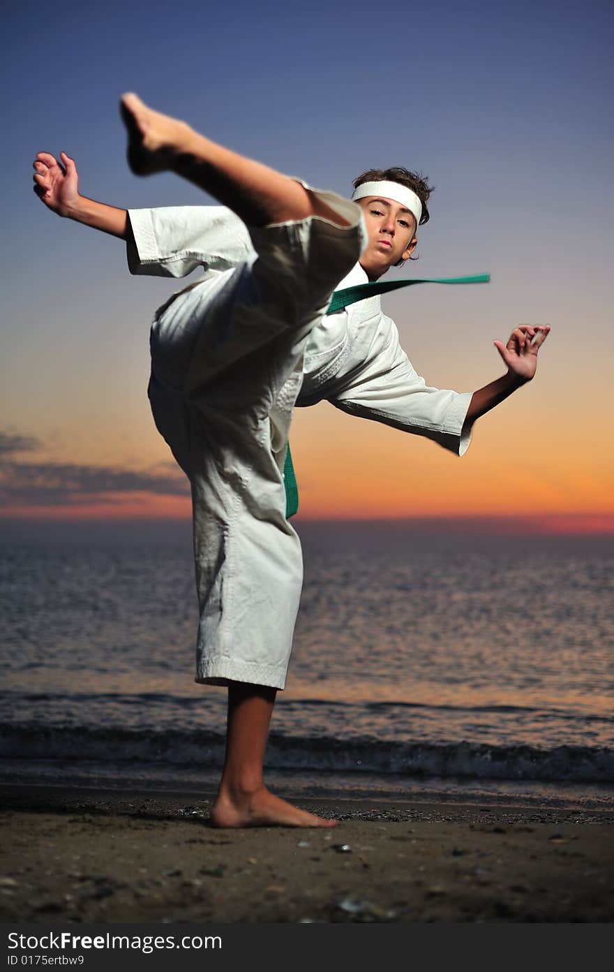 Young boy in karate uniform training at sunset. Young boy in karate uniform training at sunset