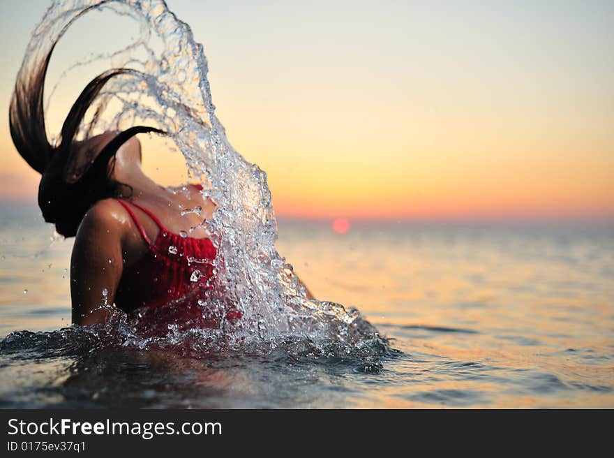 Young girl in red dress breaking out from sea. Young girl in red dress breaking out from sea