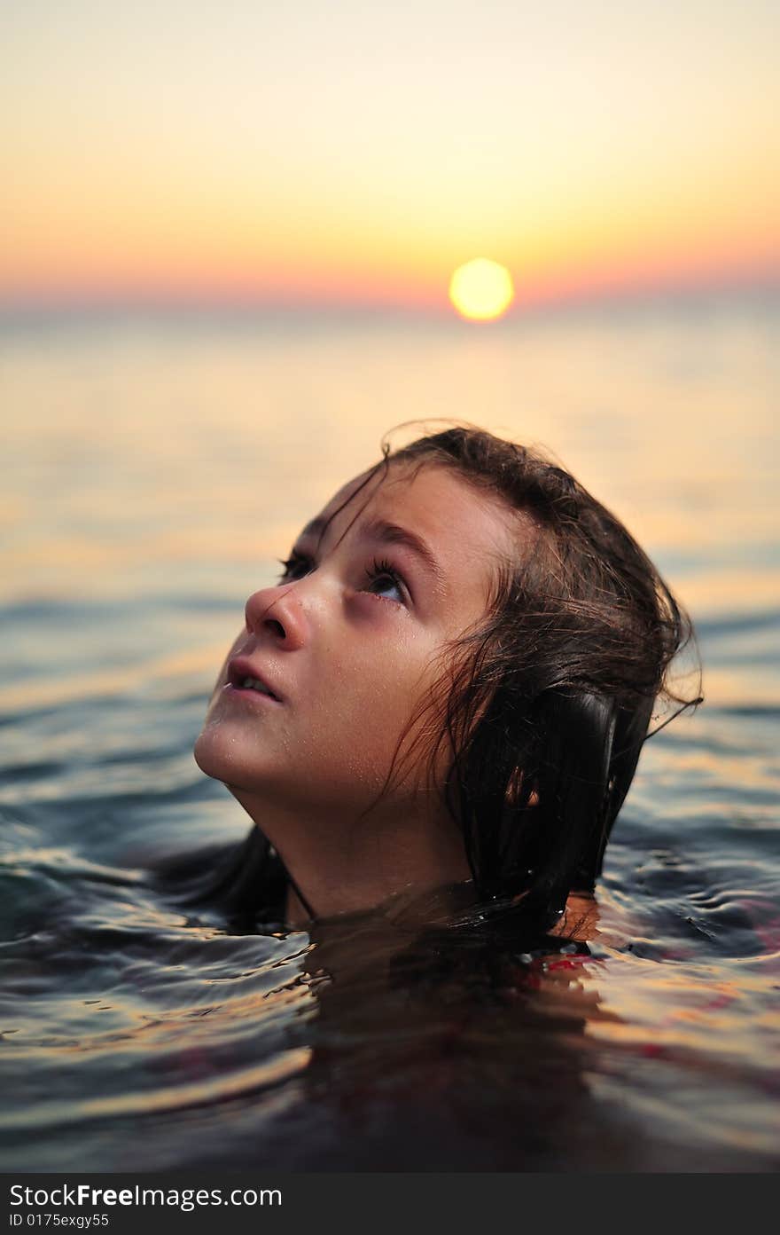 Young girl in red dress standing in sea at sunset. Young girl in red dress standing in sea at sunset