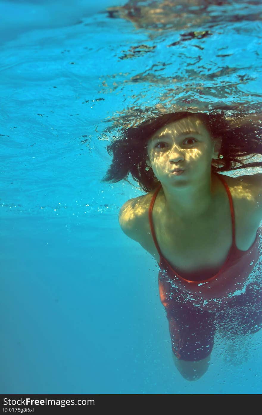 Little girl swimming underwater in pool