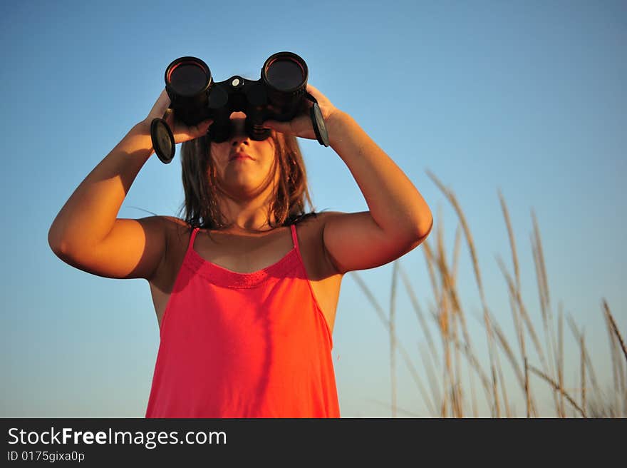 Young girl looking through binocular, low angle view. Young girl looking through binocular, low angle view