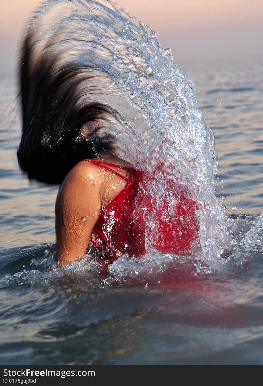 Young girl in red dress breaking out from sea. Young girl in red dress breaking out from sea