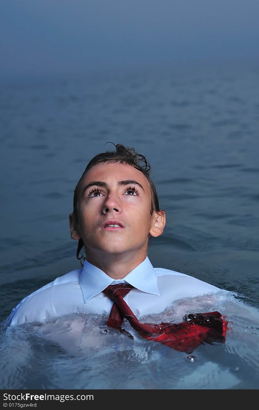 Young businessman standing on sea and looking up. Young businessman standing on sea and looking up