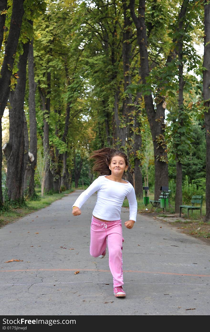 Young girl running on alley in a park