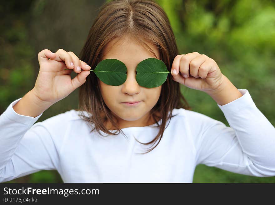 Little girl holding two leaf on eyes