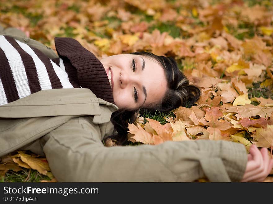 Attractive brunette woman lying on leaves. Attractive brunette woman lying on leaves