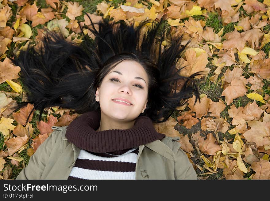 Attractive brunette woman lying on leaves. Attractive brunette woman lying on leaves