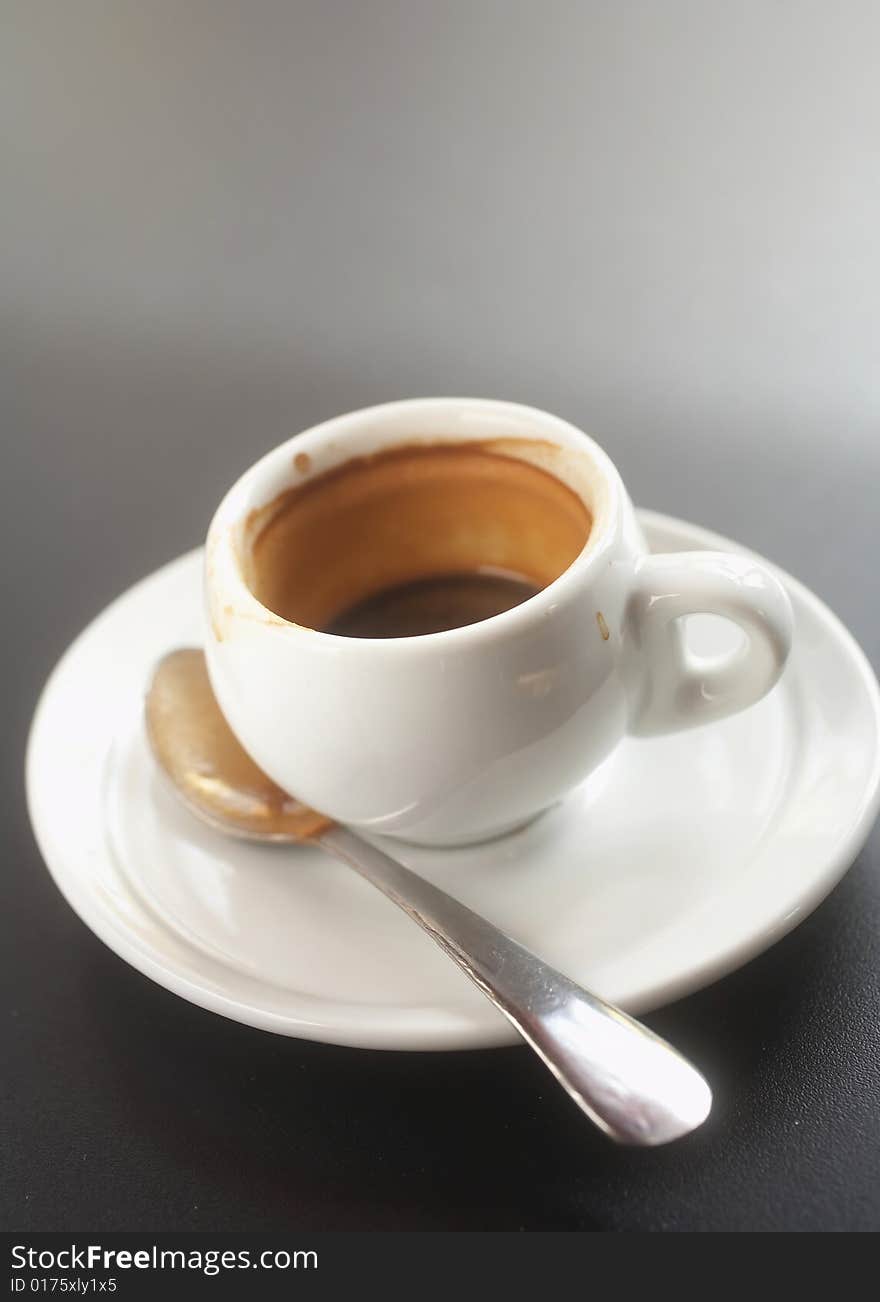 Shot of espresso and spoon on saucer