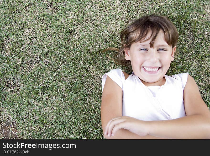 Smiling young cute girl lying on the grass