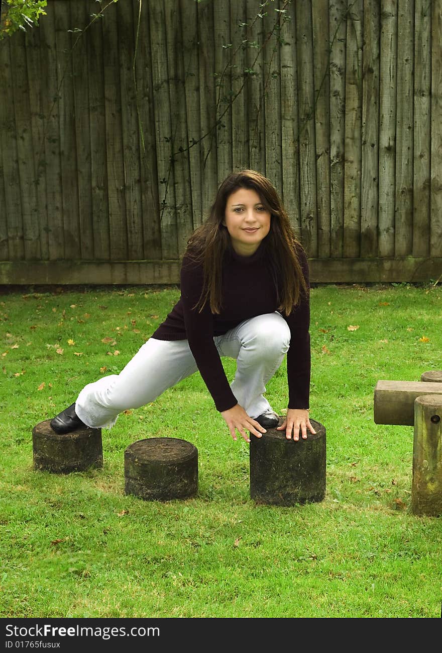 Woman climbing over stepping stones in the playground. Woman climbing over stepping stones in the playground.