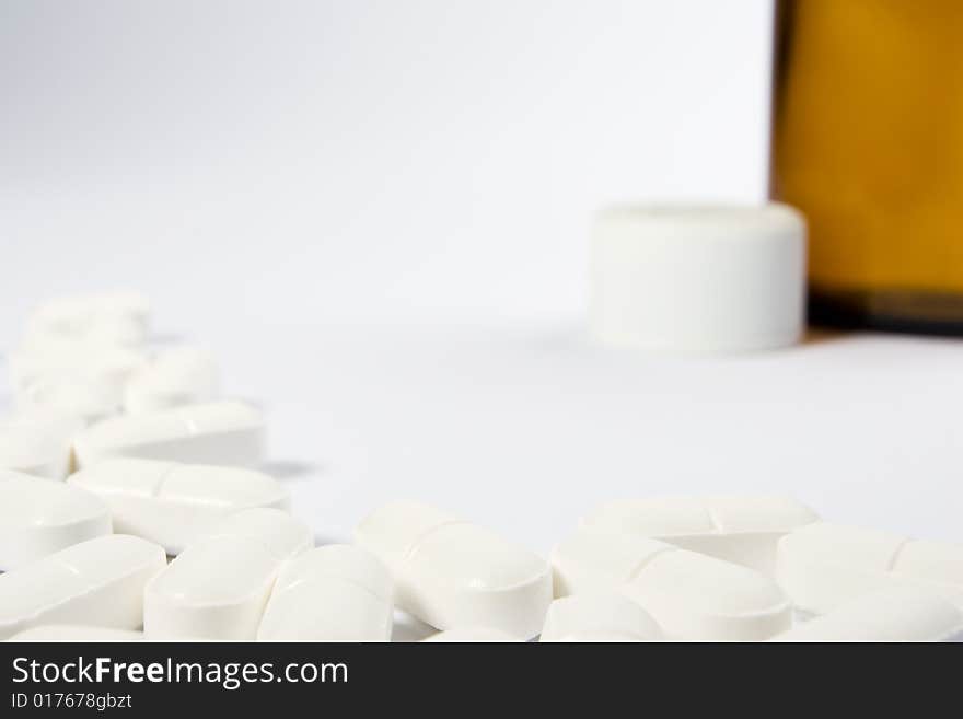 A border of pills on the left-hand side and lower part of a white frame with an opend bottle in the top right-hand area. A border of pills on the left-hand side and lower part of a white frame with an opend bottle in the top right-hand area