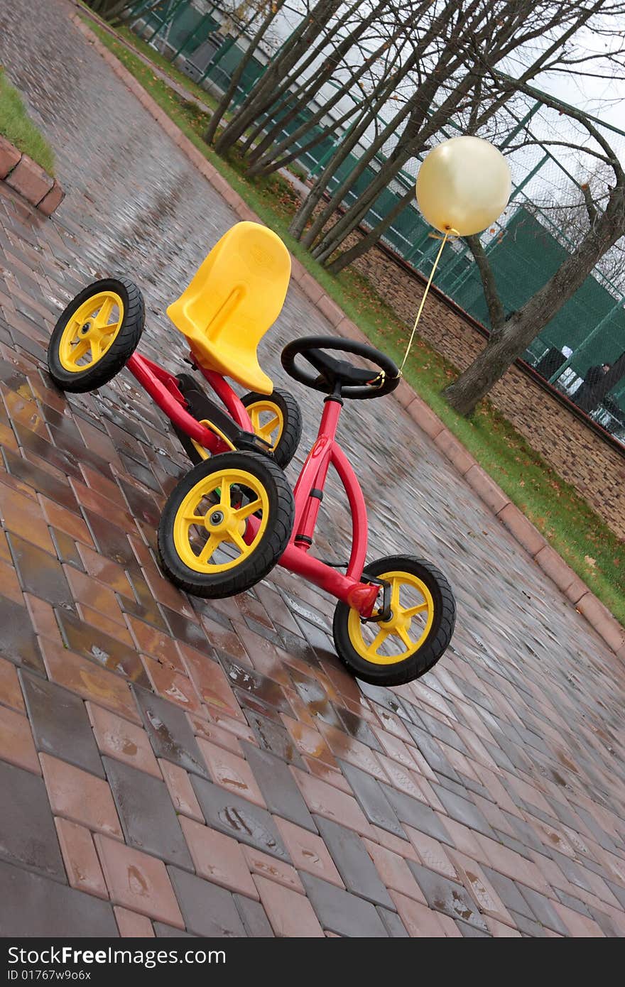 The four-wheel bicycle with yellow ball on pavement. The four-wheel bicycle with yellow ball on pavement