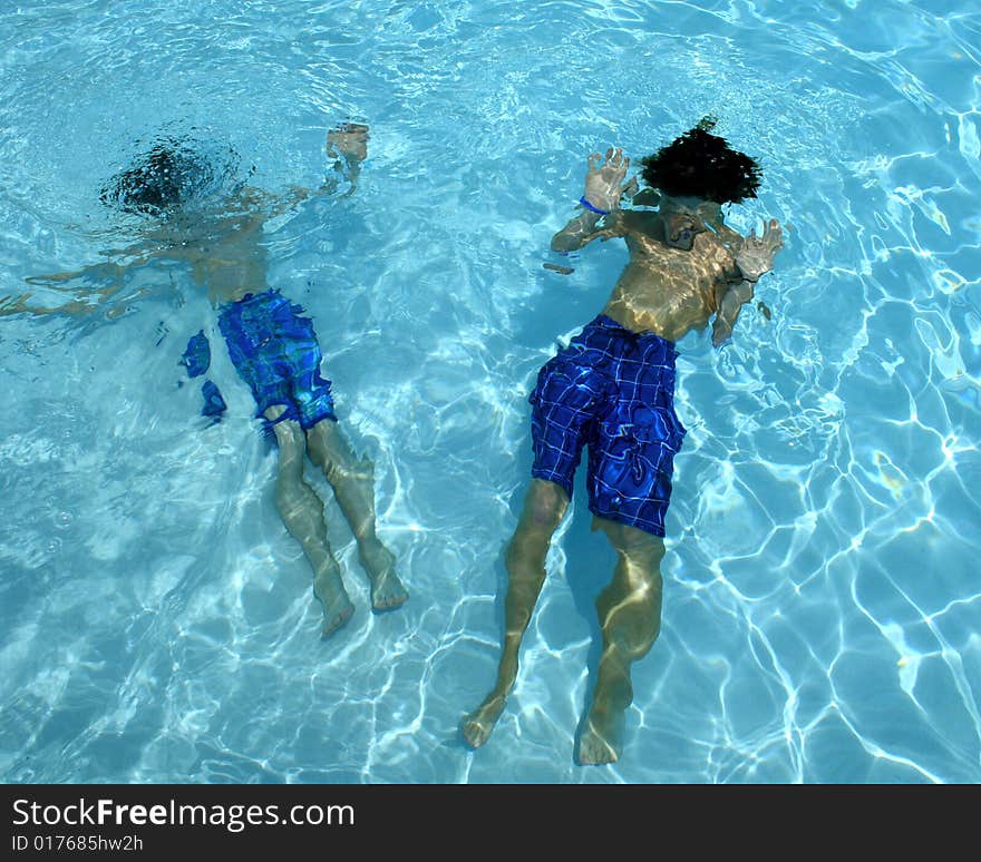 Image of boys floating underwater in pool. Image of boys floating underwater in pool