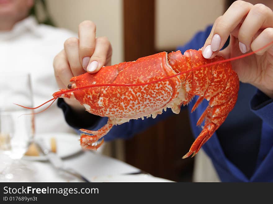 The girl holds a lobster in a restaurant