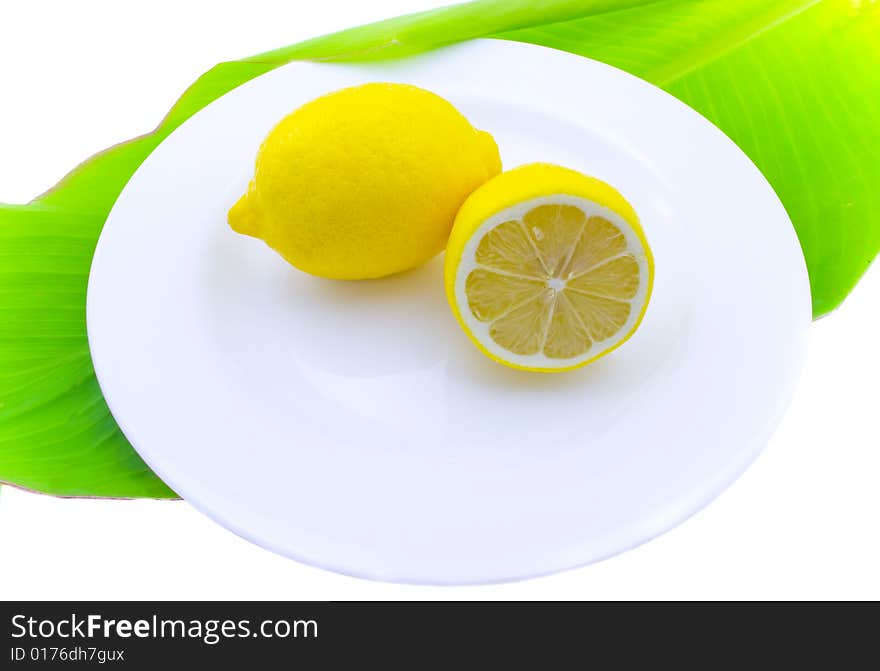 Whole and a lemon half on a white plate. Whole and a lemon half on a white plate